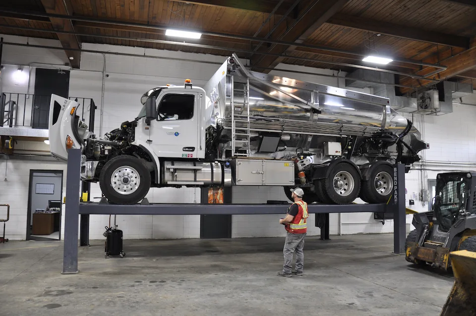 A dump truck being worked on lifted in a shop.