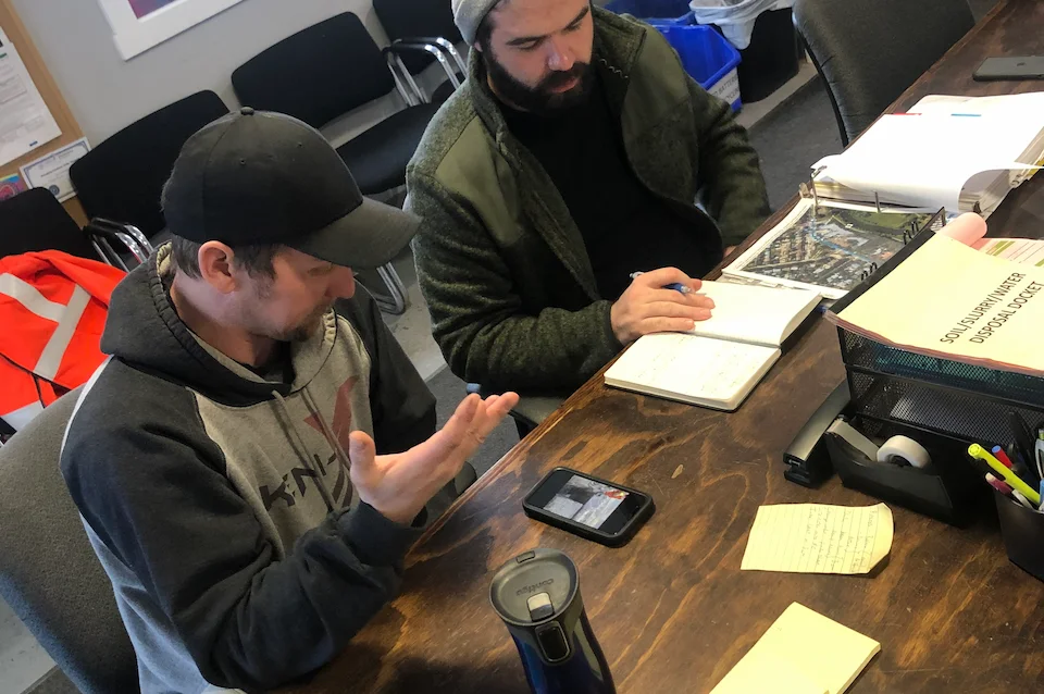 Employees sitting at a desk discussing a plan with notes in front of them.