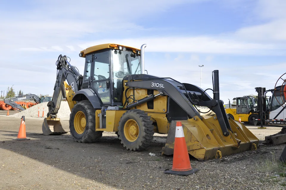 A relatively close view of a yellow John Deere 310 SL excavator with a bucket on the front and scoop on the back.